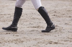 Rider walking a course at horse jumping competition. Boots details
